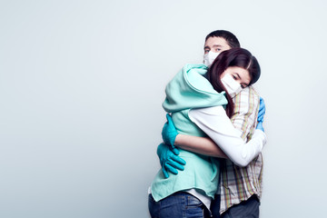Man and woman in medical mask and medical gloves hug each other.