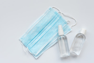 Surgical medical face mask, bottles of antiseptic hand gel and spray on white background.  Flu, illness, pandemic concept