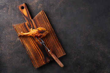 Roasted chicken legs and meat fork on a white plate. View from above.