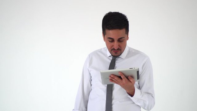 A satisfied man looks at a digital tablet and is upset by what he saw. The distressed man raises his eyebrows and grabs his head