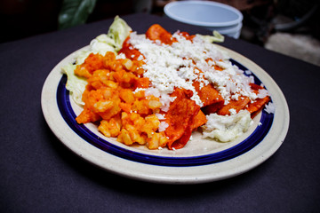 Enchiladas, platillo típico mexicano. Hecho con chiles guajillos y tortillas. Acompañado de cebolla, crema, queso, zanahorias, ppapas y lechuga