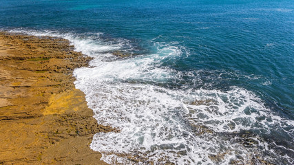 Waves of turquoise water washed by the rocky stone coast of Portugal. Aerial view.
