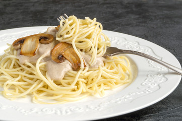 Spaghetti with mushrooms in cream sauce. on dark background