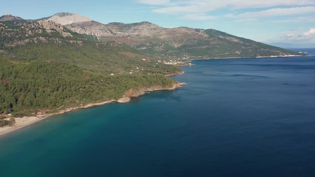 Drone flight around the mountain slopes and rocky coastline of Thasos island and the little island Nisida Kinira, Greece