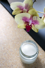 Delicate orchid flowers on a background of tejsklany jars with natural homemade organic yogurt.