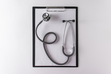 Stethoscope and blank clipboard with a sheet of paper.