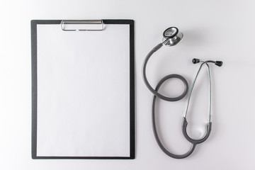 Stethoscope and blank clipboard with a sheet of paper.