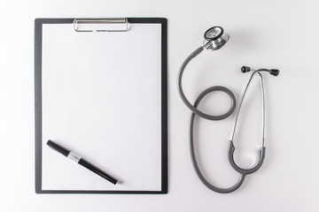 Stethoscope, pen and blank clipboard with a sheet of paper.