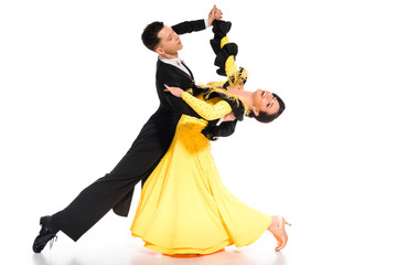elegant young couple of ballroom dancers in yellow dress and black suit dancing on white