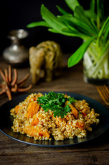 Bulgur with pumpkin on a wooden table. Vegetarian recipes from Indian cuisine.