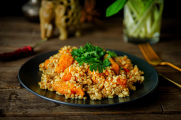 Bulgur with pumpkin on a wooden table. Vegetarian recipes from Indian cuisine.