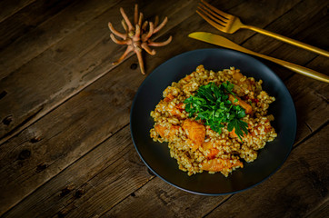 Bulgur with pumpkin on a wooden table. Vegetarian recipes from Indian cuisine.
