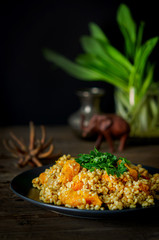 Bulgur with pumpkin on a wooden table. Vegetarian recipes from Indian cuisine.