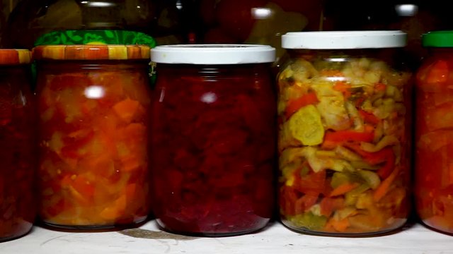 Glance slides along row of glass jars of pickled vegetables in pantry