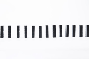 Black dominoes lined up. Domino effect. Structural instability