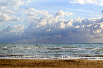 Sandy beach on a sunset against a cloudy sky