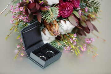Wedding bridal bouquet. Wedding silver rings in a black box. beautiful bride and groom ring in white gold with engraving close up. wedding day. wedding details.