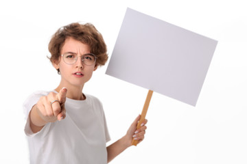 Concerned female protester holding empty signboard with copy space pointing at camear at the viewer