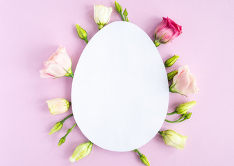 Easter creative composition.  Flat lay with shape of easter egg, frame  of flowers on pink  background. Minimal spring concept. Copy space