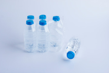 Close-up shot of plastic bottles of water in transparent wrap on white surface