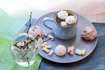 Fototapeta na wymiar A cup of coffee, meringues, a bouquet of flowering branches of a cherry tree on a windowsill, spring, morning, home relaxation