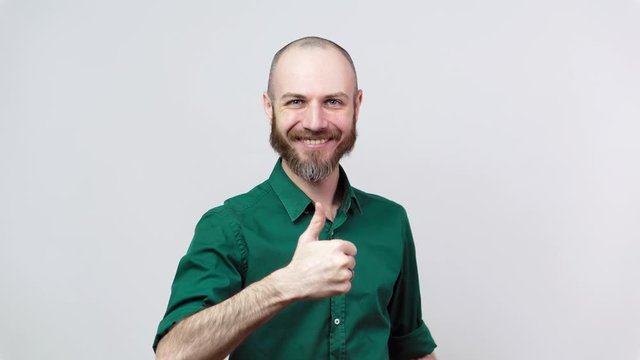 Happy bearded man in shirt showing thumbs sign up over white background. Good job, very well.