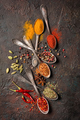 Different spices, dry kitchen herbs and seeds in vintage spoons for tasty meals