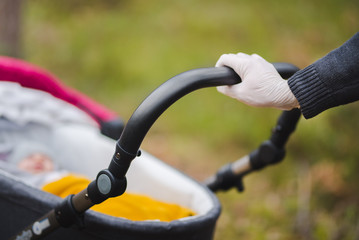 A man on a walk with a baby troller and hands in gloves