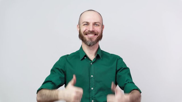 Happy bearded man in shirt showing thumbs sign up over white background. Good job, very well.