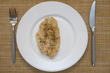 Chicken breast chop on a white plate.