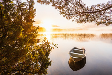 Rowboat on still lake at sunrise