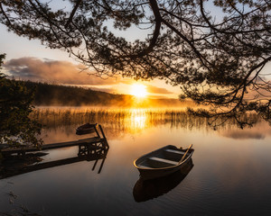 Row boat on still lake at sunrise