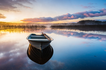 Boat on calm lake at sunrise