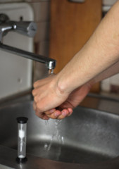 man washing his hands in kitchen sink, sand clock