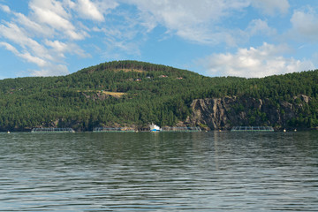 Norwegian fjords sea mountain picturesque landscape with cloudy blue sky, Lysefjord, Norway, fish farms near coast.