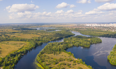 Fototapeta na wymiar sunny summer day over green islands on a river in a northern city - Aerial Fligh