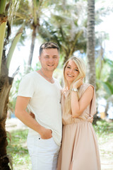 Portrait of an attractive man with a girl against the background of nature. Photo of travelers posing near palm trees.