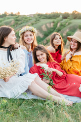 Fototapeta premium Happy relaxing friends on picnic in park, young beautiful girls having fun while spending time together in the summer garden. Women outdoor friendship concept. 
