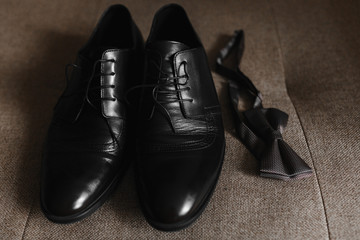 Man black leather shoes and bowtie on the brown background