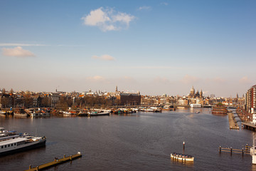 Panoramic Amsterdam city view with canals and boats in autumn with clouds and blue sky