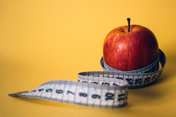 Healthy lifestyle concept. Red apple with measuring tape. Dieting concept.