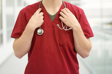 Closeup caucasian man doctor with stethoscope on neck, weared in red medical outfit