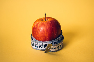 Healthy lifestyle concept. Red apple with measuring tape. Dieting concept.