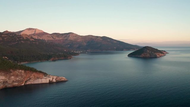 Drone flight around the mountain slopes and rocky coastline of Thasos island and the little island Nisida Kinira, Greece