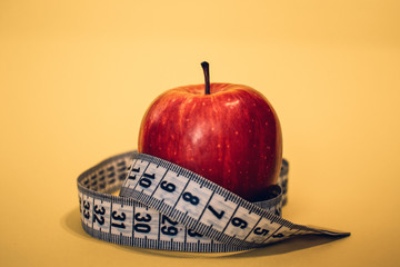 Healthy lifestyle concept. Red apple with measuring tape. Dieting concept.