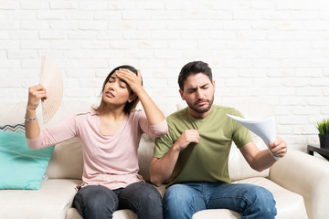 Hispanic Couple Feeling Hot In Living Room During Summer