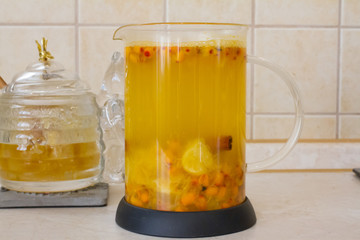 Vitamin useful sea buckthorn tea in a glass teapot with fresh sea buckthorn berries, orange, cinnamon sticks and honey. The concept of rest, relaxation. top view with a copy of the space