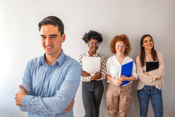 Portrait of a young designer standing in an office with his colleagues in the background. Cropped shot of a businessman standing in the office with his arms folded looking confident