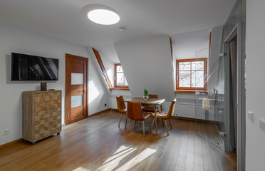 Modern contemporary interior of living room with furniture and tv. Sloping ceiling. Private house.