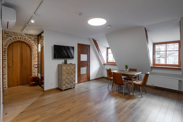 Modern contemporary interior of living room with furniture and tv. Sloping ceiling. Private house.